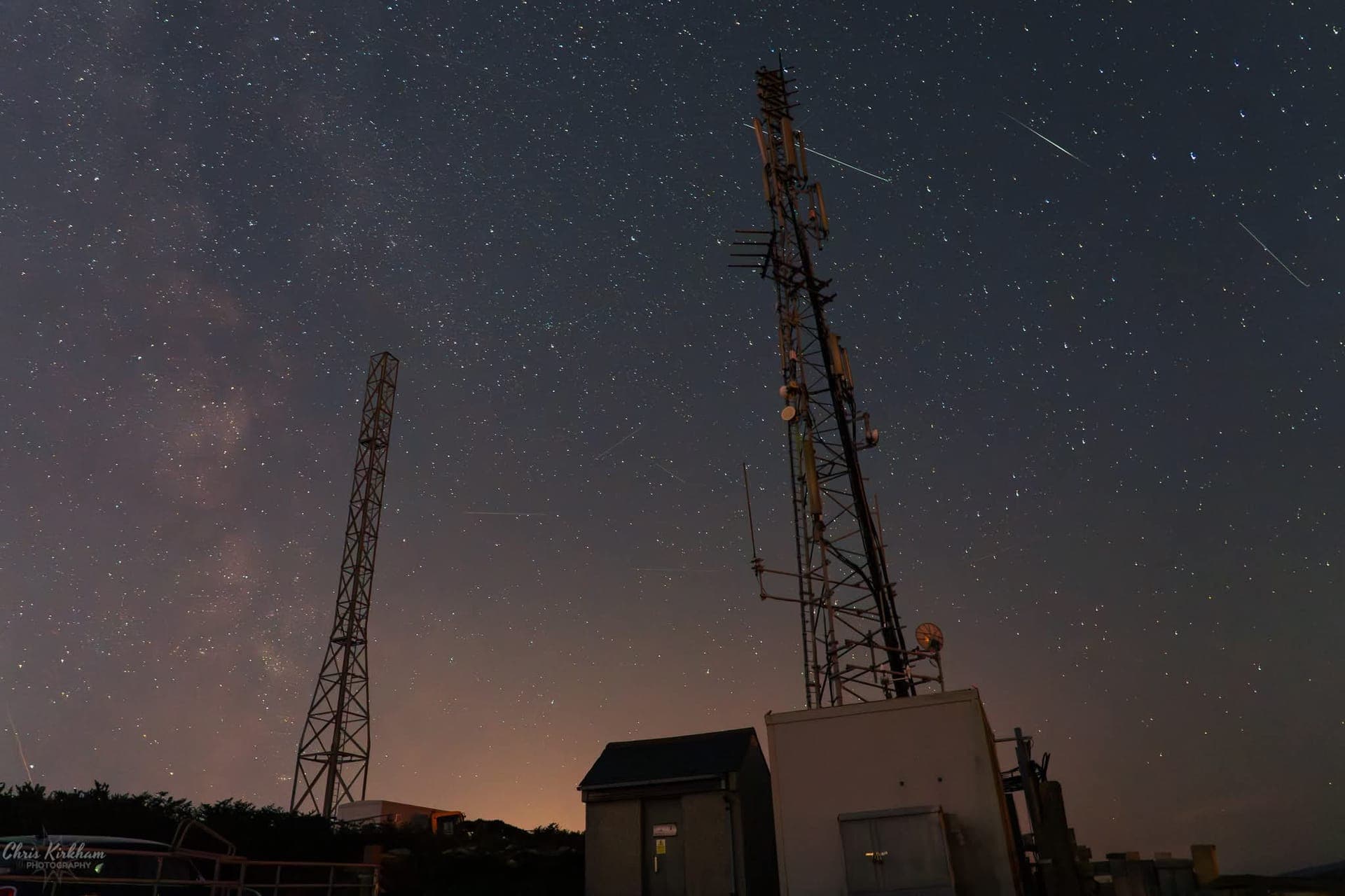 Two radio masts silhouetted against a starry night sky
